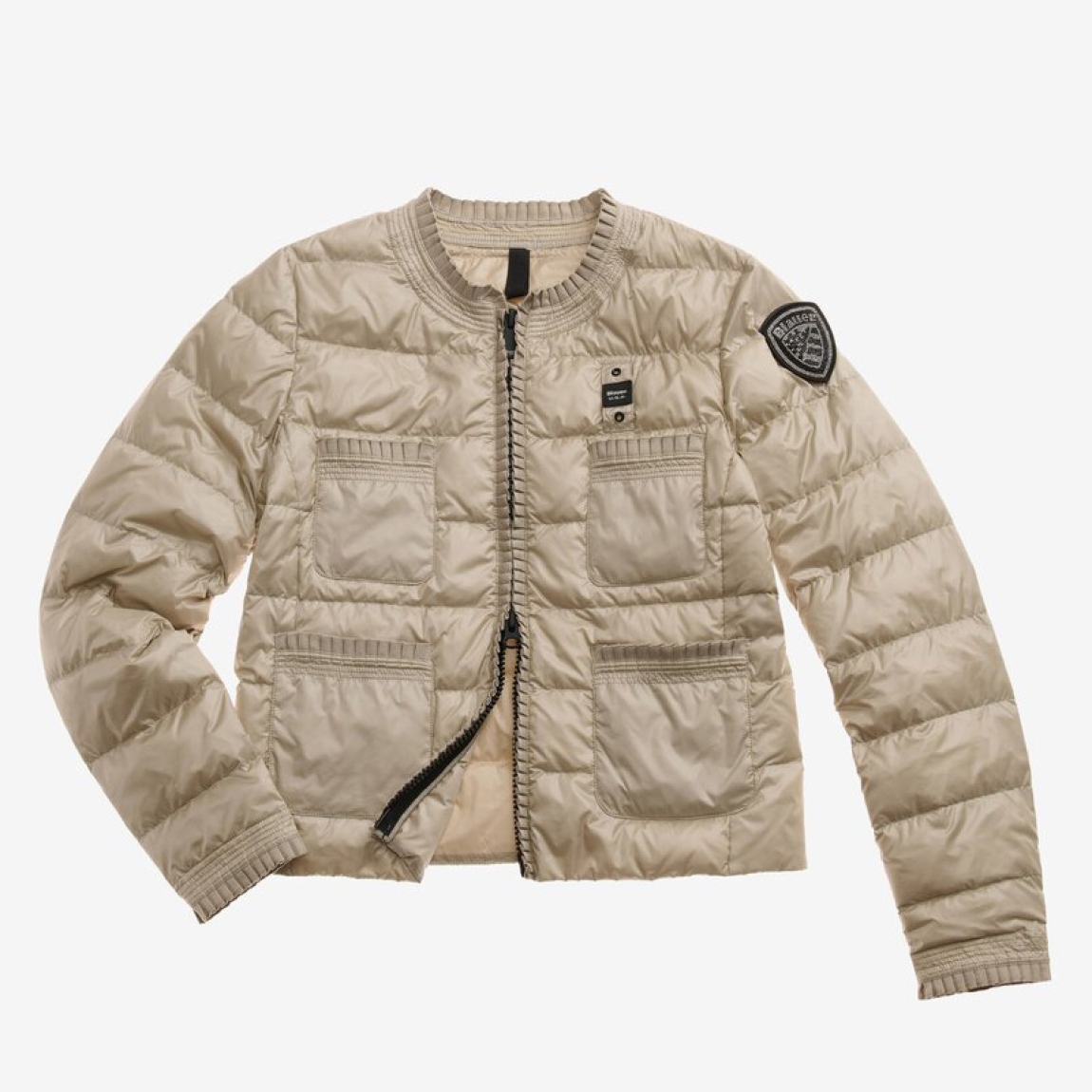 Chaqueta acolchada de la marca Blauer, modelo ROSE. Plumífero corto elaborado en naylon color beig. Chaqueta Blauer de cuello redondo con costuras en rayas horizontales. La chaqueta corta está adornada con una cinta plisada que le da a la prenda un estilo clásico y refinado. Cierre con cremallera. Acolchado con plumón 90/10  47 gr. Cuatro bolsillos. Bolsillo interior con velcro. Parche y pasante con logotipo. Chaqueta Blauer ideall para esta temporada!