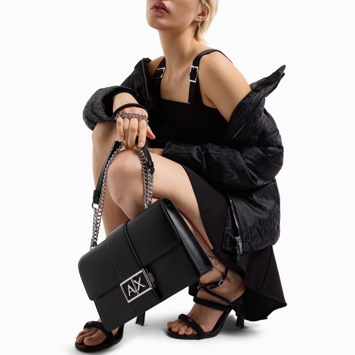 Este bolso de hombro de la marca Armani Exchange, modelo AVA, está elaborado de piel sintética color negro. E un accesorio elegante y sofisticado, perfecto para cualquier ocasión. La correa de cadena para el hombro añade un toque de clase, mientras que el logotipo de metal en la parte delantera aporta un detalle distintivo y moderno. El cierre a presión garantiza seguridad y comodidad, manteniendo el contenido seguro. Compacto pero espacioso, este bolso es ideal para una apariencia elegante y versátil, combinando funcionalidad y estilo en un diseño refinado. Un artículo imprescindible para cualquier mujer que busque elegancia. Medidas: alto 16cm y acho 25cm.