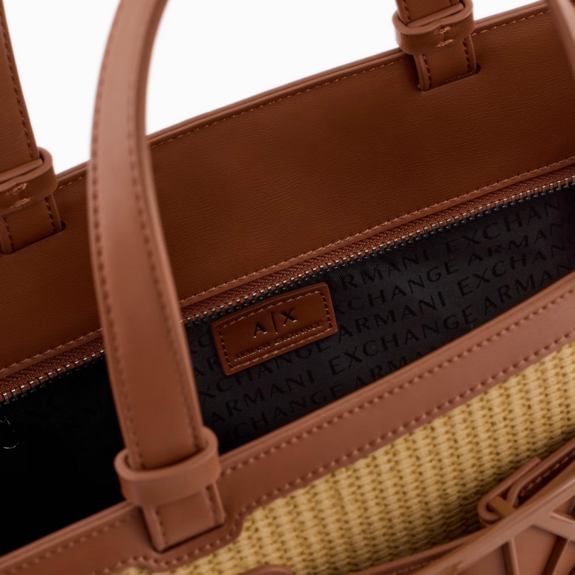 Bolso trenzado de la marca Armani Exchage, modelo TILSA. Exterior en rafia color camel, con logo en parte frontal. Cierre con cremallera, y doble asa, fija y regulable para máxima comodidad. Bolso con amplio espacio interno. Medidas: alto 24cm y ancho 32cm. Este bolso Armani Exchange TILSA es un complemento ideal para esta temporada!