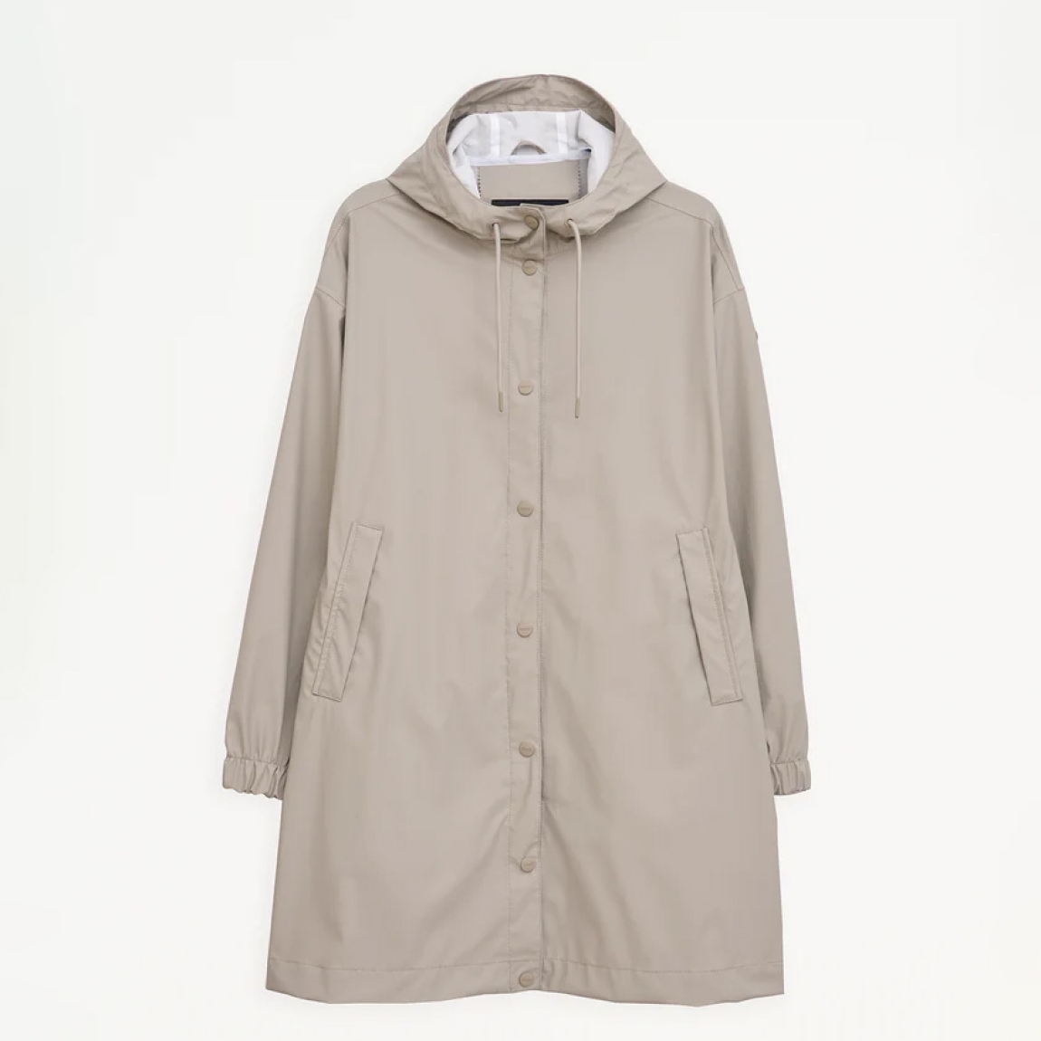 Chaqueta impermeable de la marca Tanta, modelo Mis. Es un chubasquero de corte holgado y diseño siempre contemporáneo 100% impermeable. Está confeccionada con un tejido ligero de PU color beig y cuenta con todas las costuras selladas para una protección superior. Los detalles de la prenda incluyen botones a presión, una capucha con visera incorporada y bolsillos con ribetes. Ideal para esta temporada!