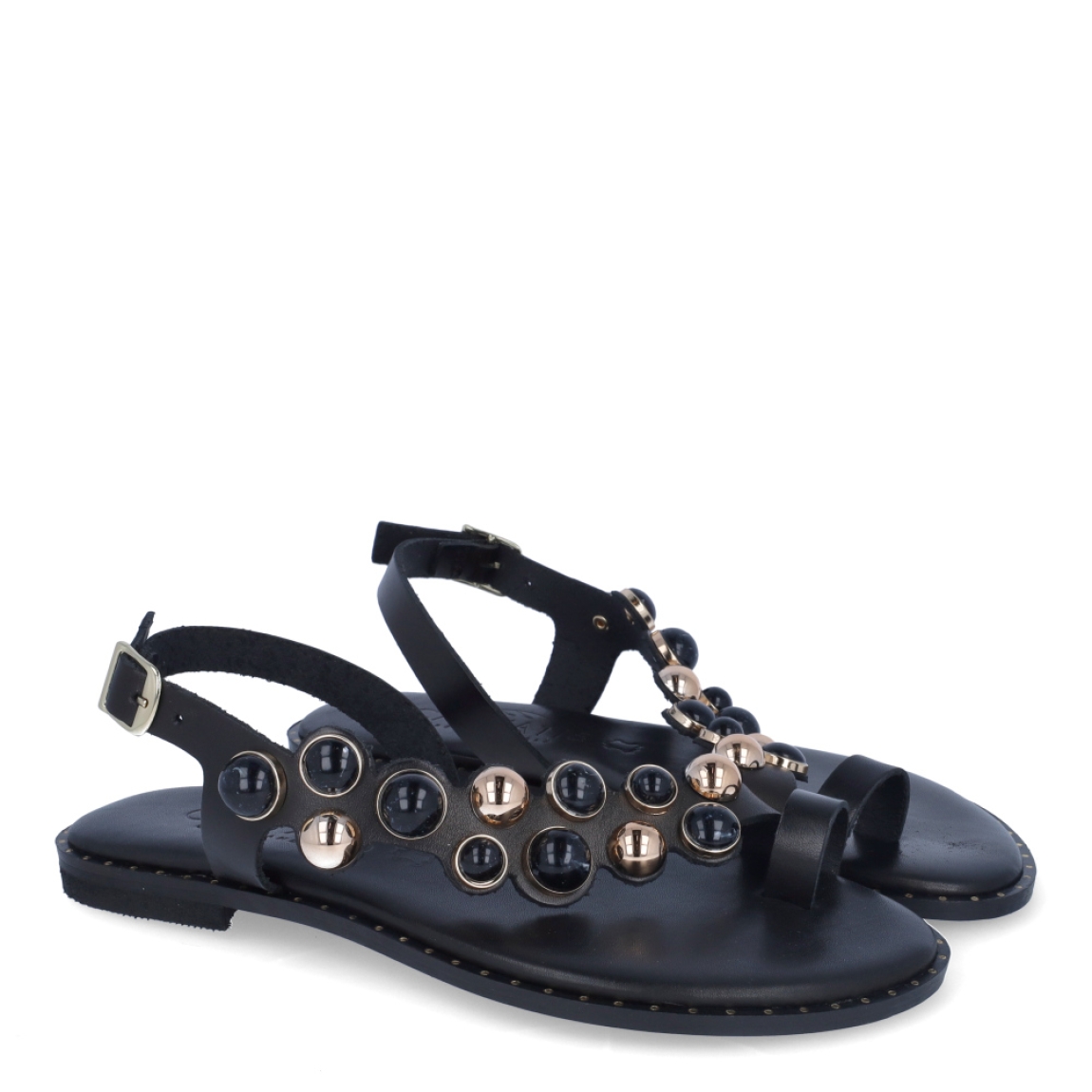 Esclavas de la marca Caryatis, modelo SENDRA. Exterior de las esclavas en piel color negro con adornos en piedrería. Cierre de las esclavas con hebilla y suela plana. Estas esclavas Caryatis SENDRA es un producto de alta calidad, pensado en la comodidad y elegancia. No puede faltar en tu armario de temporada.