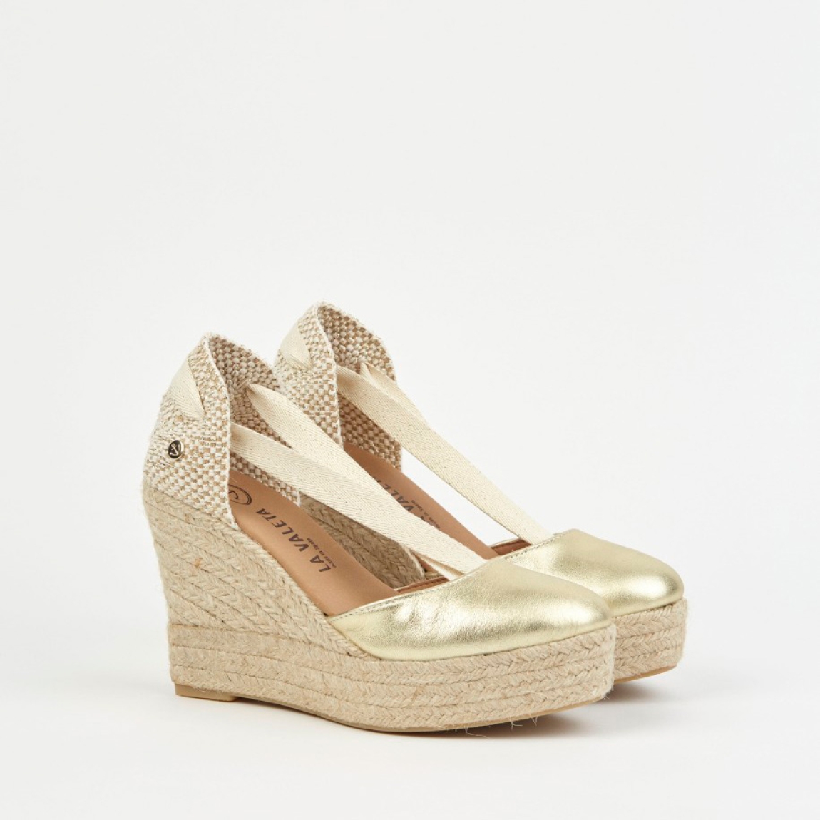 Alpargatas de la marca La Valeta, modelo CHARLENE. Exterior en piel color oro con punta redonda, forrada en microfibra transpirable. Plantilla de microfibra transpirable acolchada. Alpargatas con tiras de tela para un cierre con nudo. Plataforma en yute artesanal con cuña de 10cm de altura. Estas alpargatas La Valeta CHARLENE son ideales para esta temporada!