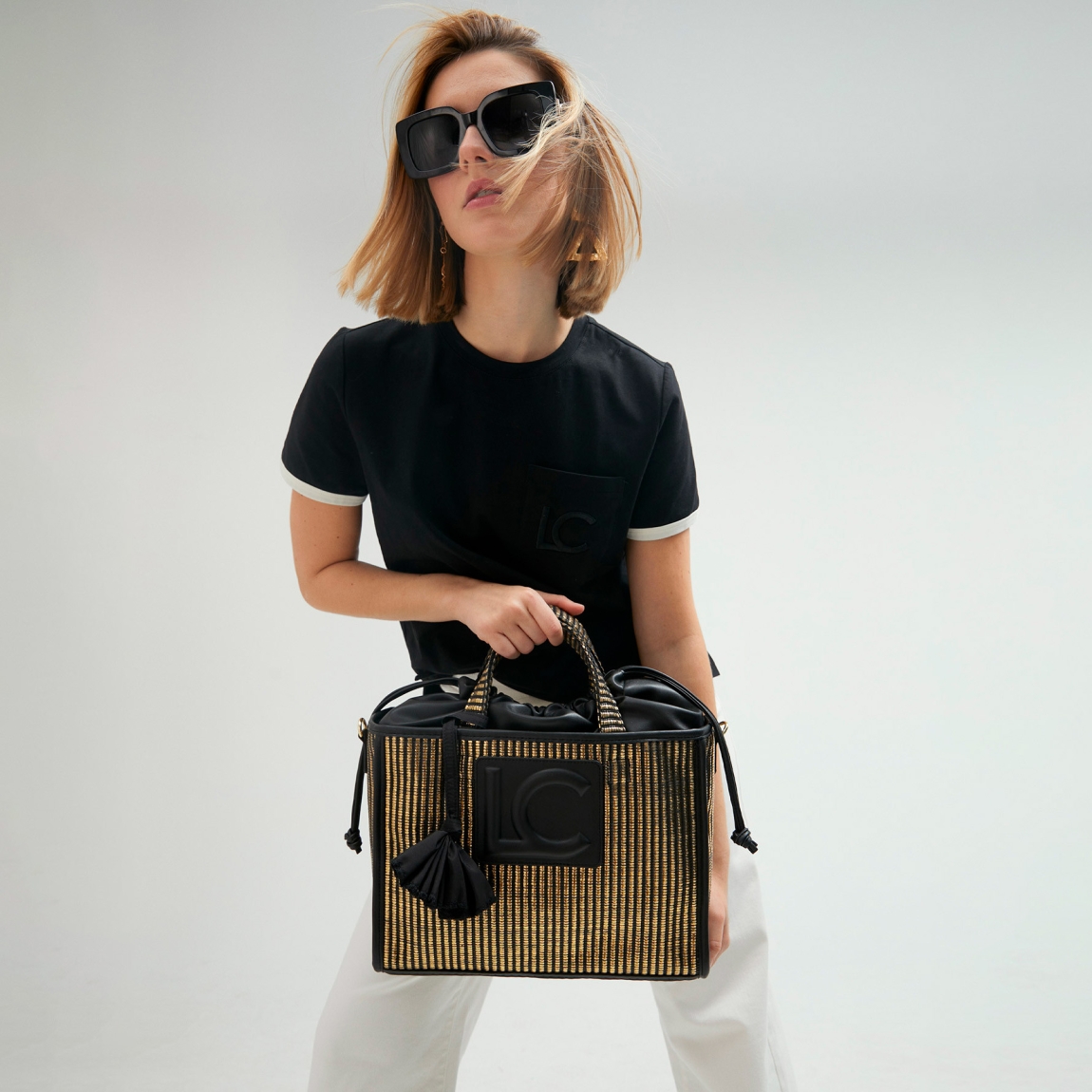 Bolso de la mara Lola Casademunt, modelo BLERO. Elaborado en rafia con efecto metalizado color oro con logo grande de marca en parte frontal color negro. Contiene bolsillo interior y asa bandolera. Cierre ajustable con cordón. ALTO: 26 cm - LARGO: 11 cm - ANCHO: 34 cm / BANDOLERA: 120 cm
