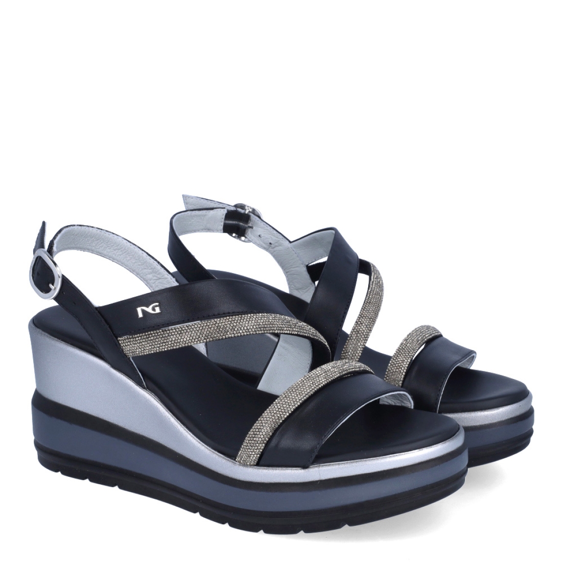 Sandalias de la marca Nerogiardini, modelo SOFF. Exterior de las sandalias en piel color negro con detalle de tiras brillantes color plateado en la pala. Interior de las sandalias en piel color negro. Cierre de las sandalias Nerogiardini con hebilla en tobillo. Sandalias con cuña de 8cm de altura. Estas sandalias Nerogiardini SOFF son un complemento clásico, inspirado en la comodidad, ligereza que necesitas en tu día a día.