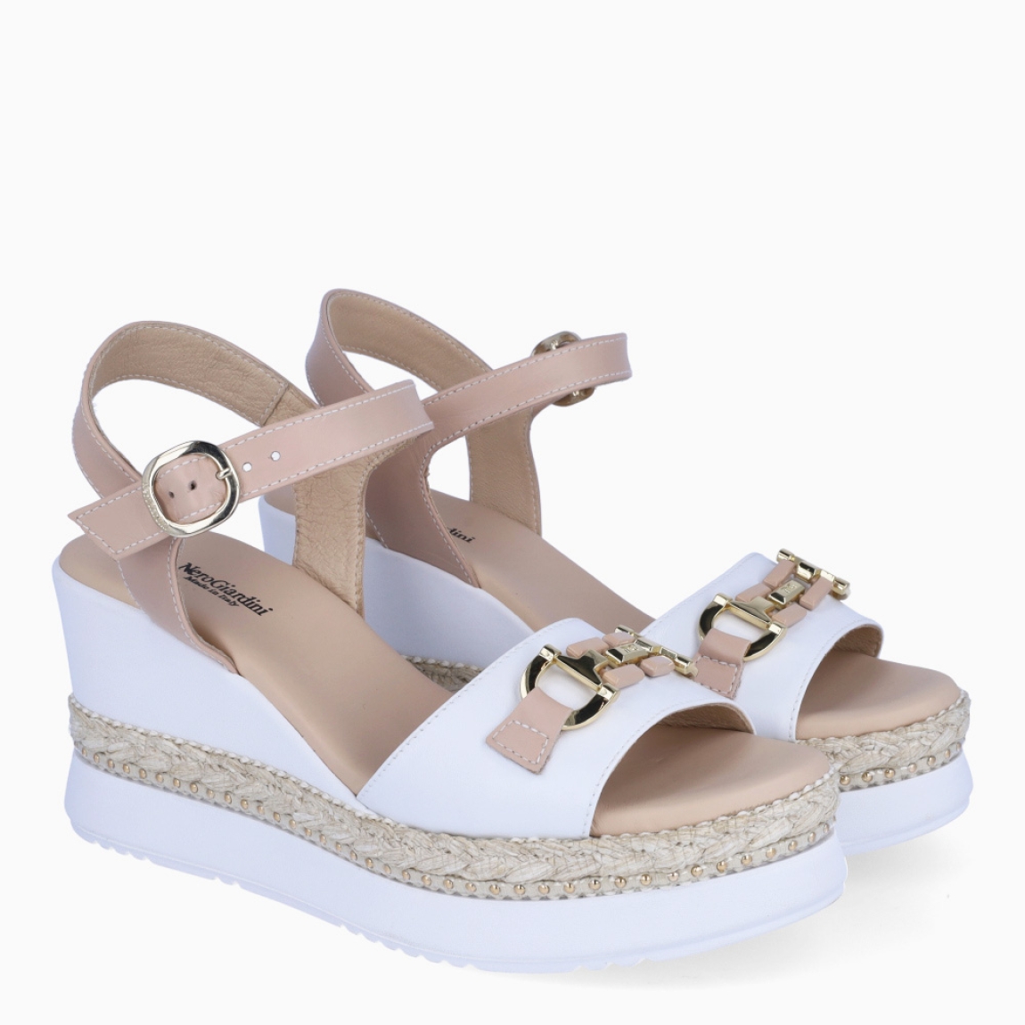 Sandalias de la marca Nerogiardini, modelo LUA. Exterior de las sandalias en piel color blanco con detalle de cadenas doradas en la pala. Interior de las sandalias en piel color nude. Cierre de las sandalias Nerogiardini con hebilla en tobillo. Sandalias con cuña de 8cm de altura. Estas sandalias Nerogiardini LUA son un complemento clásico, inspirado en la comodidad, ligereza que necesitas en tu día a día.