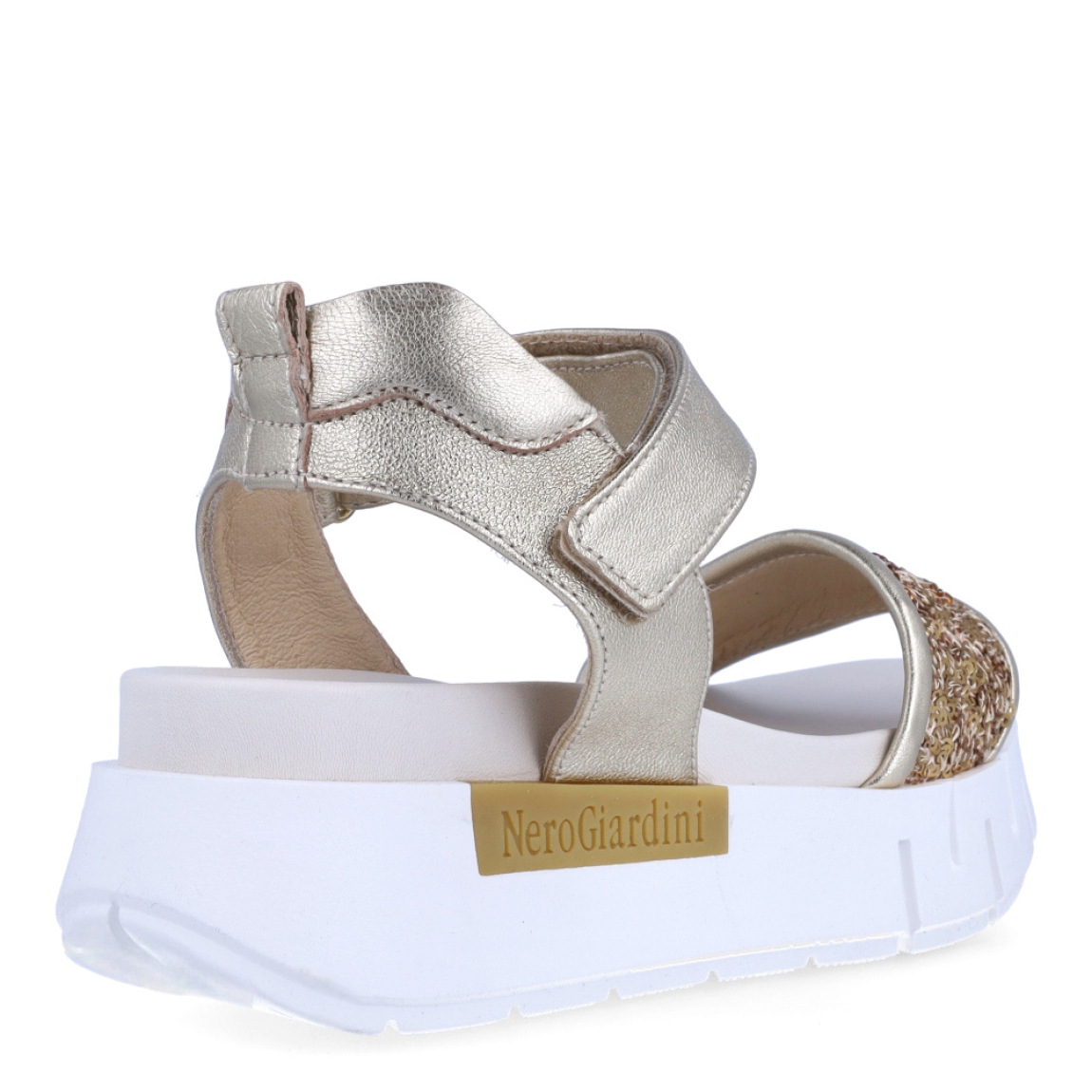 Sandalias de la marca Nerogiardini, modelo JESS. Exterior de las sandalias en piel color platino con detalle de lentejuelas color dorado en la pala. Interior de las sandalias en piel color blanco. Cierre de las sandalias Nerogiardini con velcro. Sandalias con plataforma de 4cm de altura. Estas sandalias Nerogiardini JESS son un complemento clásico, inspirado en la comodidad, ligereza que necesitas en tu día a día.