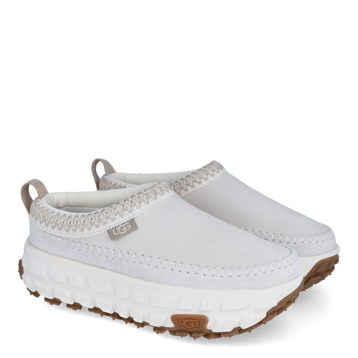 Zuecos de la marca UGG, modelo Venture Daze. Exterior en es ante color hielo. Zuecos diseñados para ofrecer un aspecto atrevido y comodidad. El Venture Daze cuenta con una suela de agarre con grandes bandas de rodadura de neumáticos para la tracción todo terreno. La parte superior de ante, el clásico UGGbraid y las emblemáticas costuras en forma de caja se asientan sobre una ligera plantilla de EVA y una entresuela de caña. Estos zuecos UGG son ideales para ir a todos lados!