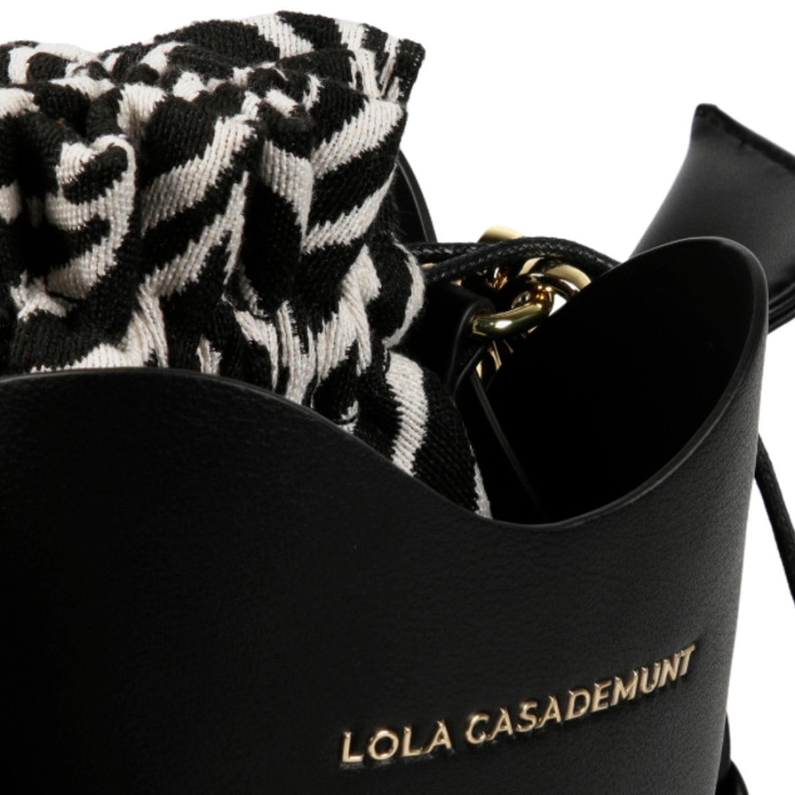 Bolso de la marca Lola Casademunt, modelo BOMB. Exterior en piel color negro con asa corta trenzada. Incluye saco interior con estampado cebra, asa larga y cierre ajustable con cordón. Medidas alto 18cm y ancho 18cm. Este bolso Lola Casademunt BOMB es ideal para llevarlo a todos lados!