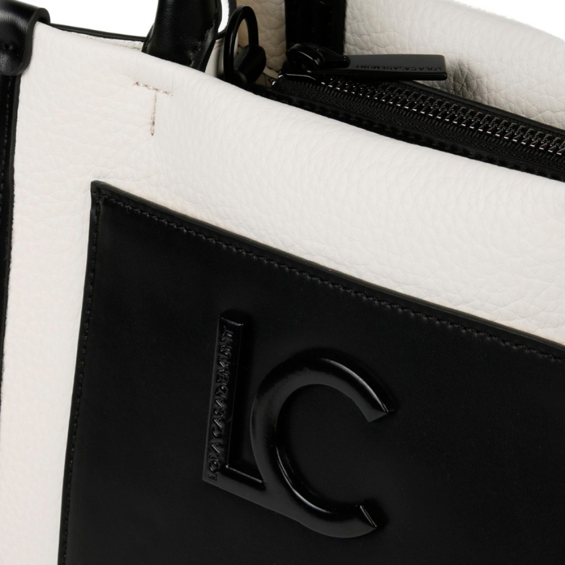 Bolso pequeño de la marca Lola Casademunt, modelo ZYNE. Exterior bicolor en efecto piel blanco y negro. Con asa bandolera y bolsillo interior. Cierre con cremallera. Medidas: alto 18 cm, largo 23,5 cm, ancho 13,5 cm. Bandolera de 135 cm de largo. Este bolso Lola Casademunt ZYNE es ideal para llevar a todos lados!