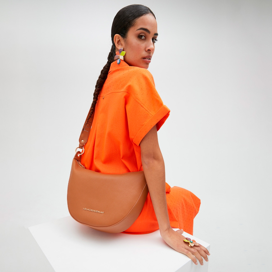 Bolso bandolera mini hobo de la marca Lola Casademunt, modelo ANAHI. Exterior en efecto piel color camel y detalles de tachuelas planas. Contiene compartimento interior y asa bandolera troquelada. Cierre con cremallera.ALTO: 21 cm - LARGO: 38 cm - ANCHO: 10 cm / BANDOLERA: 87 cm