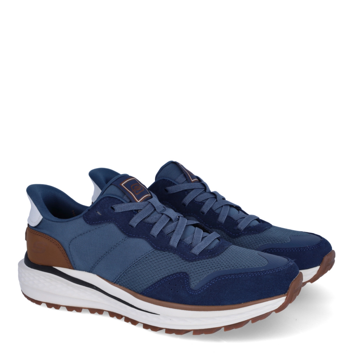 Deportivas de la marca Skechers, modelo 211. Exterior en naylon con efecto rejilla color azul marino, con detalle en marrón en talón. Interior en textil transpirable color azul oscuro con plantilla acolchada y extraíble para máxima comodidad. Cierre con cordones. Suela de goma con cuña de 2cm de altura. Estas deportivas Skechers 211 son ideales para tu día a día, unas clásicas excelentes en comodidad.