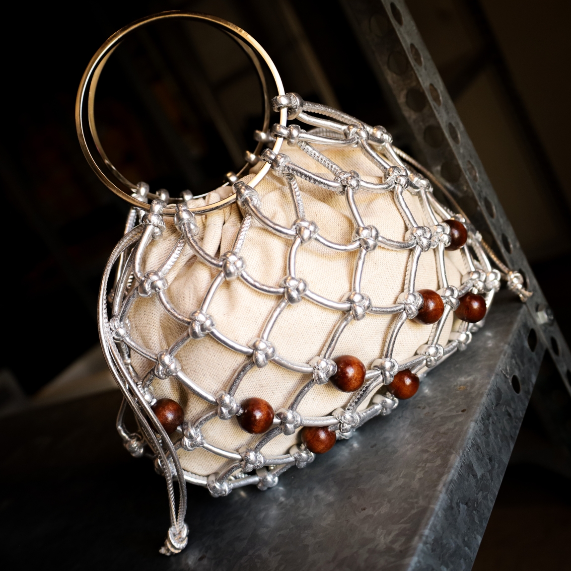 Bolso pequeño de la marca Unisa, modelo ZCOCO. Bolso con asas metálicas. Fabricado en piel metalizada color plata anudada manualmente por expertos artesanos e interior de tejido natural. Detalle de adorno. Cierre con cordón de piel metalizada al tono. Medidas: 15cm x 22cm x 11cm. Bolso ideal para las ocasiones especiales!