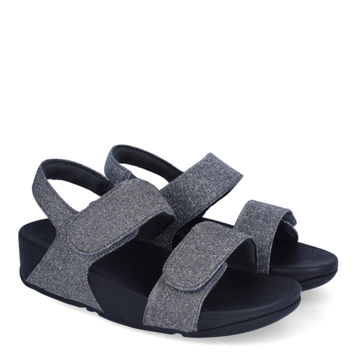 Sandalias de la marca Fitflop, modelo LULU ADJUSTABLE. Exterior en neopreno color gris, decorado con brillantes en pala. Interior en microfibra de color negro. Cierre con doble velcro en la pala. Suela de caucho antideslizante y planta acolchada. Cuña de 4 cm incluyendo 2,5 cm de plataforma. Con detalle de piel sintética perlada metalizada en los laterales. Fabulosas de día y de noche.