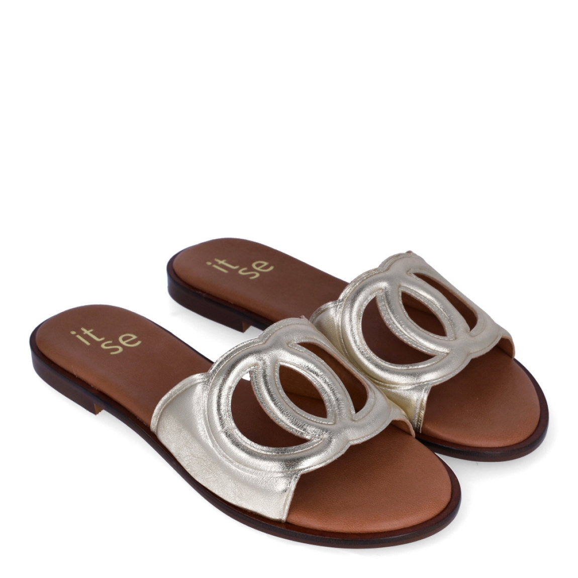 Chanclas de la marca Itse, modelo BRITNE. Exterior en piel color platino con detalle de círculos cruzados en la pala. Interior en piel color camel con logo de marca. Chanclas con suela de goma y plana. Estas chanclas Itse BRITNE son unas clásicas, ideales para combinarlas con diferentes looks esta temporada!