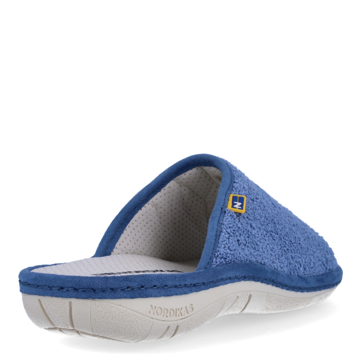Zapatillas de casa de la marca Nordikas, modelo KAYA. Exterior de las zapatillas en toala color azul. Interior de las zapatillas en piel troquelada color blanco. Zapatilla con suela plana. Estas zapatillas Nordikas KAYA son el complemento perfecto que garantiza comodidad y ligereza al estar por casa.
