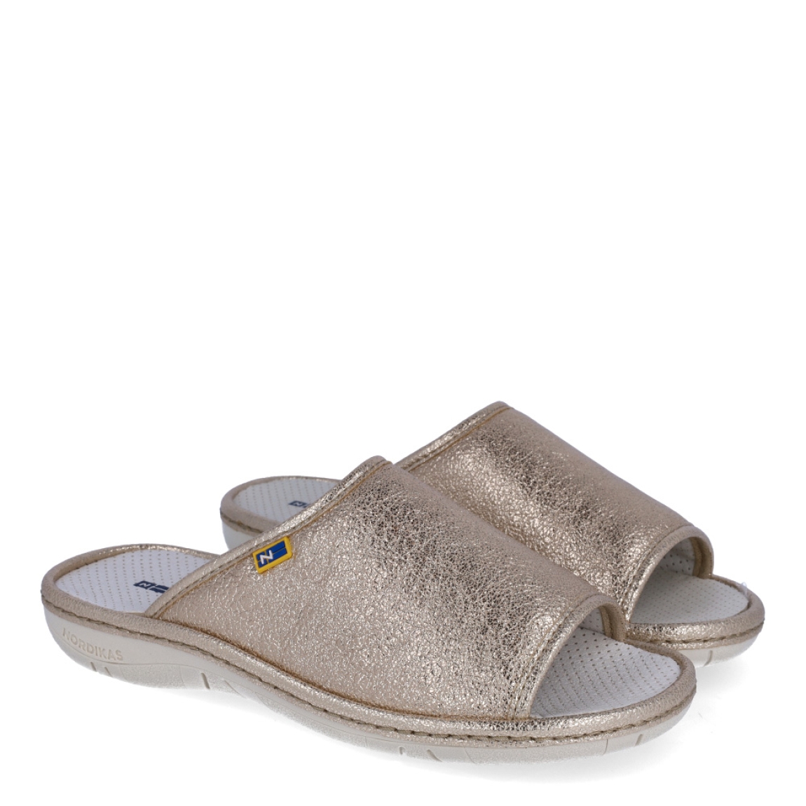 Zapatillas de casa de la marca Nordikas, modelo KAYA. Exterior de las zapatillas en piel color platino efecto serpiente. Interior de las zapatillas en piel troquelada color blanco. Zapatilla con suela plana. Estas zapatillas Nordikas KAYA son el complemento perfecto que garantiza comodidad y ligereza al estar por casa.