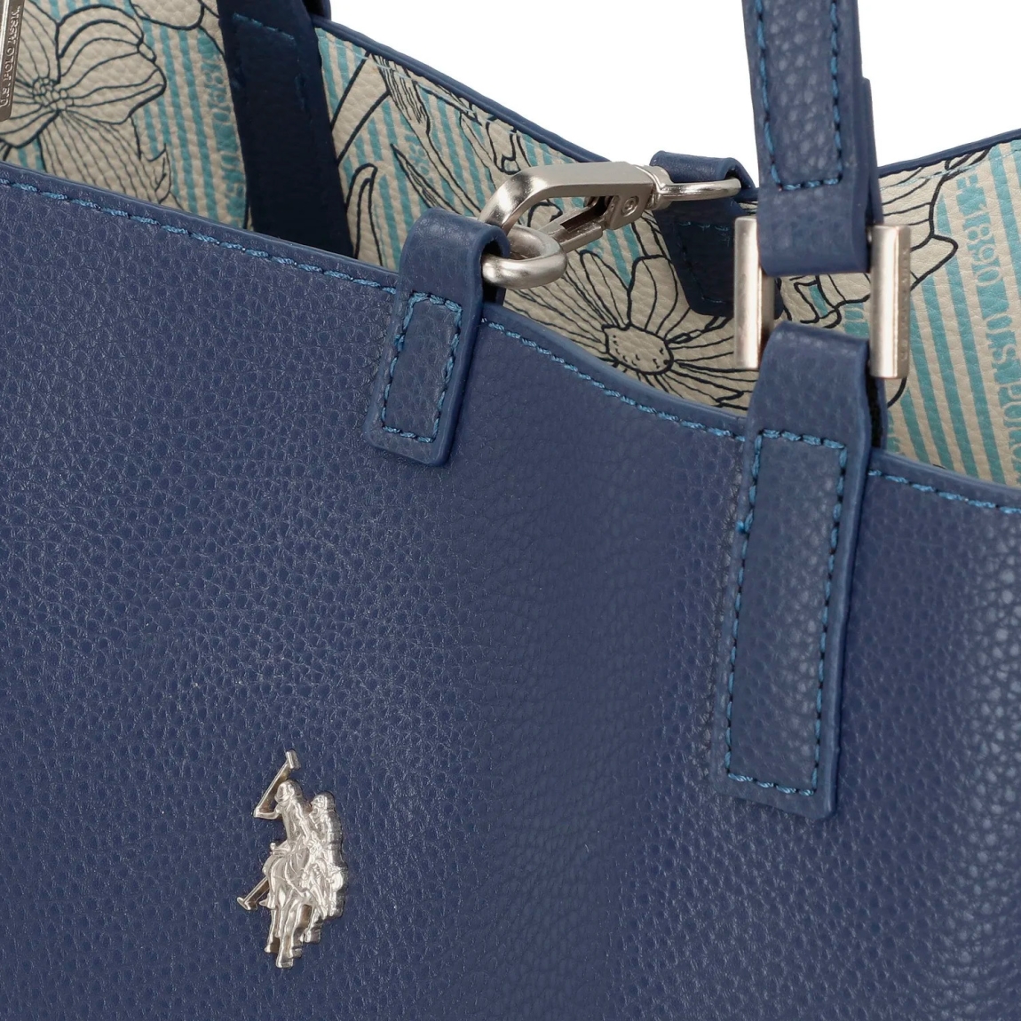 Bolso de la marca US POLO, modelo MALIBU. Elaborado en piel color azul con logotipo en parte frontal. Cierre con hebilla y forro interior de tela. El bolso shopper cuenta con un bolsillo desmontable para un uso diario estructurado, y el cierre de langosta añade un elemento práctico. La correa principal de longitud media ofrece sujeción sin concesiones. Medidas: alto 28cm y ancho 38cm. Este bolso US POLO MALIBU es un clásico para llevar a todos lados!