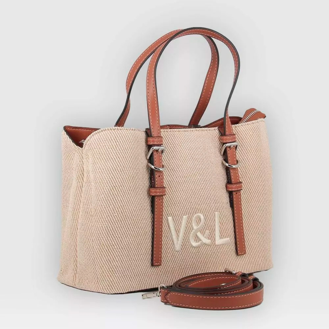 Bolso de la marca Victorio & Lucchino, modelo PAZ. Elaborado en textil color camel con logotiipo en parte frontal. Bolso clásico con cierre de cremallera y asa ajustable y extraíble para máxima comodidad. Medidas: alto 20cm y ancho 28cm. Este bolso Victorio & Lucchino es el aliado perfecto para tus días de verano! Este bolso en un encantador tono beige es el complemento ideal para cualquier atuendo, ya sea para un paseo por el parque o una cena al aire libre.