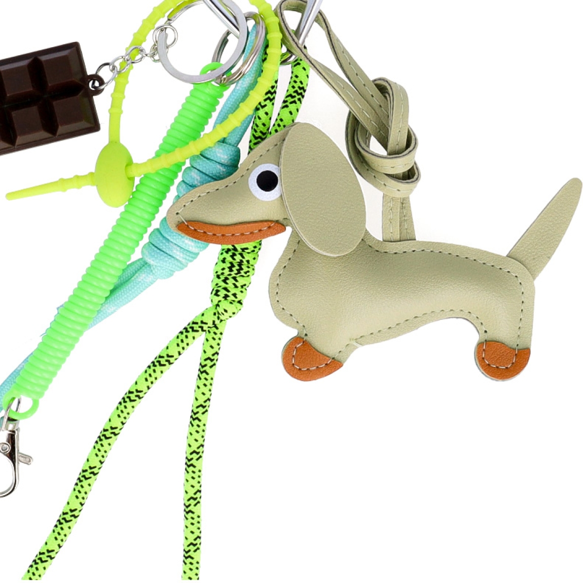 Llavero de la marca MUNNÉ, modelo DOG. Elaborado en piel color verde con dijes de chocolate y perro salchicha. Complemento perfecto para tu bolso.