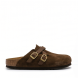 Zuecos de la marca Birkenstock, modelo BLAIR. Zuecos elaborados en piel de ante (serraje) color marrón chocolate, con detalle de tiras cruzadas en el empeine y elegantes hebillas ajustables en acabado dorado. Cuentan con la icónica plantilla anatómica de corcho y látex forrada en piel y suela plana de EVA ligera. Estos zuecos Birkenstock son ideales para complementar tus looks de temporada aunando tendencia y confort. No pueden faltar en tu armario.