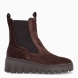 Botines estilo chelsea de la marca Tamaris, modelo BRUN. Confeccionados en suave piel de ante en un intenso tono marrón chocolate, presentan caña media con dobles tiradores y amplios paneles elásticos laterales para un calce rápido y flexible. Incorporan plantilla interior acolchada de alto confort y una ligera suela dentada con cómoda cuña de 2 cm, perfecta para aislar del frío y brindar máxima estabilidad en cada pisada. Ideales para llevar con pantalones de vestir, vestidos midi fluidos con abrigo estructurado o tejanos anchos. ¡El botín todoterreno imprescindible para vestir con estilo y confort todo el invierno!