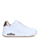 Deportivas de la marca Skechers, modelo UNO FLEX. Exterior en piel con detalle troquelado color blanco con detalle del logo en parte lateral y color bronce en talón. Interior en textil color blanco con plantilla acolchada y extraíble para máxima comodidad. Cordones de color blanco y una cuña de 3cm de altura. Estas deportivas Skechers UNO FLEX son unas clásicas, ideales para tu día a día.